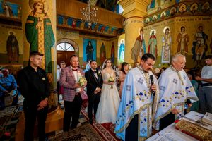 Orthodox wedding ritual being performed in a church adorned with religious icons and golden details.