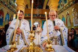 Religious ceremony taking place in an Orthodox church with golden chandeliers and painted murals.