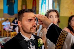Wedding ceremony attendees gathered inside a traditional Orthodox church with ornate decorations.