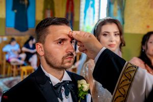 Wedding ceremony attendees gathered in an Orthodox church with traditional religious artwork.