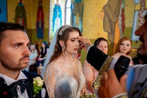 Wedding guests observe a ceremony inside a beautifully decorated Orthodox church.