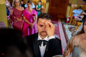 Wedding ceremony participant receiving traditional Orthodox blessing in church.