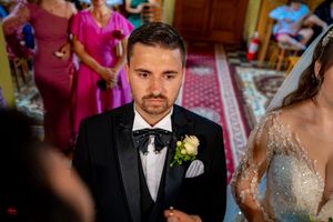 Orthodox wedding ceremony with attendees in formal attire inside ornate church.