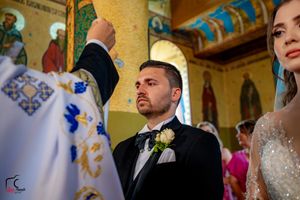 Orthodox wedding ceremony taking place in an ornate church with colorful frescoes and traditional decorations.