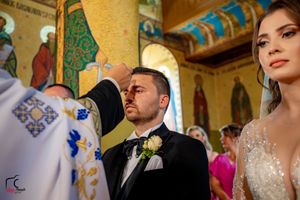 Traditional wedding ceremony in a Byzantine-style church with golden walls and painted religious icons.
