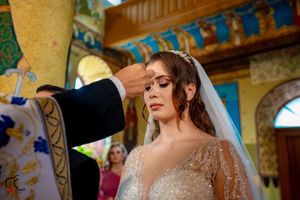 Wedding ceremony inside a richly decorated Orthodox church with vibrant murals and golden details.