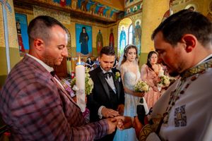 Wedding ceremony participants gathered in a beautifully decorated Byzantine church interior.