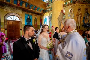 Orthodox church interior with painted saints and golden walls during a wedding ceremony.