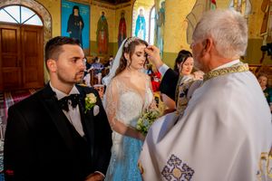 Religious wedding ceremony taking place beneath painted murals in a traditional Orthodox church.