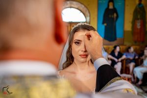 A bride in a sparkling wedding dress being photographed in a church with colorful walls and artwork.