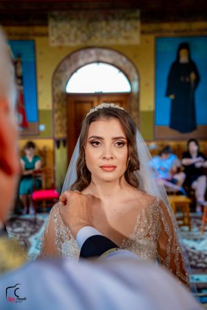 Bride in beaded wedding gown photographed against yellow church walls and artwork.