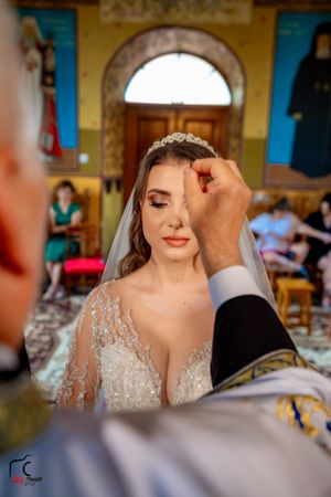 A close-up shot during a wedding ceremony shows a traditional red bindi being applied in an ornate church setting.