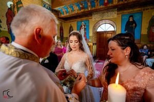 Wedding ceremony in an ornate Orthodox church with painted walls and religious icons.