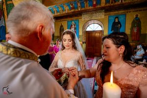 Traditional wedding ceremony taking place in a beautifully decorated Orthodox church with painted walls.