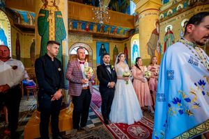 Wedding celebration in an Orthodox church featuring ornate architecture and vibrant blue ceiling artwork.