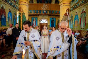 Wedding ceremony participants in white robes gather in an elaborately decorated Orthodox church.