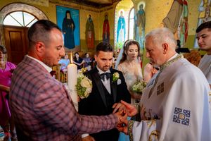Wedding ritual being performed by clergy in traditional Orthodox church with painted icons.
