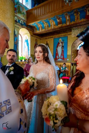 Orthodox wedding ceremony with candles and religious icons in beautifully decorated church interior.