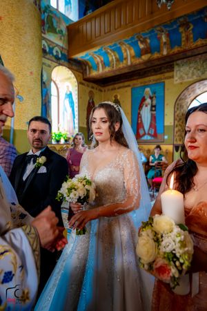 Traditional Orthodox wedding service taking place in ornately decorated church with painted icons.