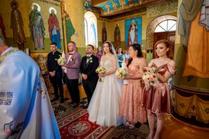 Traditional wedding ceremony taking place in a Byzantine-style church with elaborate wall paintings.