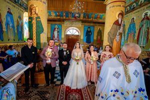 Religious wedding service in a richly decorated Orthodox church with painted saints and golden accents.