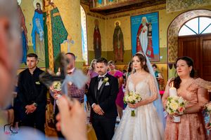 Orthodox church wedding ceremony with religious artwork and icons adorning the walls.