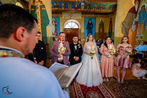 Wedding ceremony in progress inside an Orthodox church with painted saints and golden details.