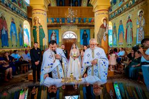 Orthodox wedding ceremony with clergy in white robes inside a beautifully decorated church.