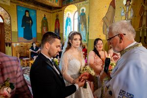 Wedding ritual being performed by clergy in traditional Orthodox church surrounded by religious icons.