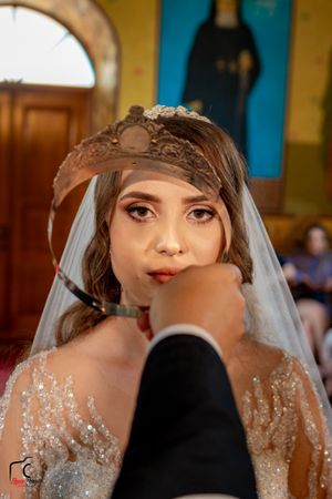 Close-up shot of a bride wearing a sparkling dress and delicate headpiece in a church setting.
