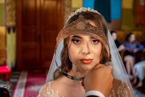 Bride in an embellished gown with decorative headpiece during church ceremony.