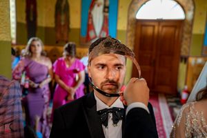 Wedding couple exchanging vows in front of ornate religious iconography during Orthodox ceremony.