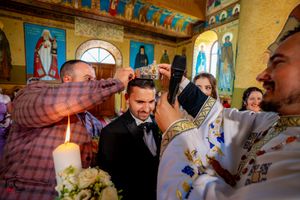 Religious wedding ceremony in Byzantine-style church with painted murals and arched windows.