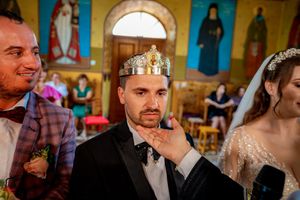 Intimate moment during Orthodox wedding ceremony with traditional crowning ritual.