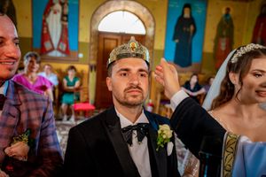 Wedding party gathered in ornate Orthodox church during traditional ceremony.