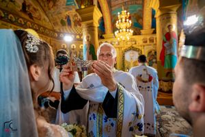Ornate church interior with golden walls and chandeliers during Orthodox wedding ceremony.