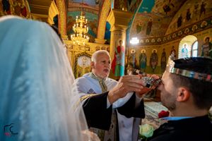 Traditional Orthodox wedding ceremony takes place in richly decorated church with golden walls.