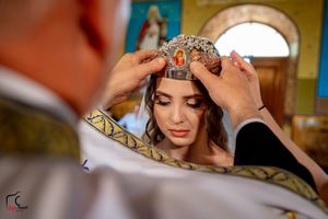 Intimate moment during Orthodox wedding ceremony with decorative crown placement.