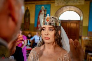 Wedding ceremony in progress inside a beautifully decorated Orthodox church with colorful religious artwork.