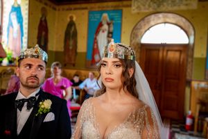 Orthodox wedding ritual being performed in front of religious icons and decorative church walls.