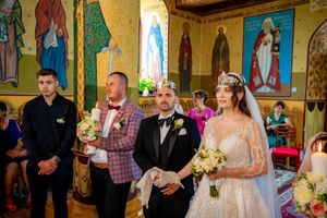 Orthodox Christian wedding service with guests gathered in traditionally decorated church interior.