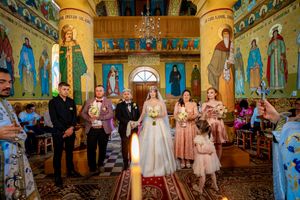 Panoramic view of a wedding ceremony in an Orthodox church with elaborate Byzantine-style murals and architecture.