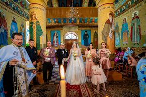 Wide angle shot of a traditional Orthodox wedding ceremony with attendants in a richly decorated church interior.