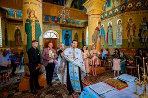 Wedding party gathered in an Orthodox church with stunning religious artwork and golden architectural details.