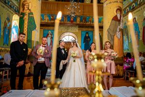 Orthodox wedding ceremony in an ornate church with gold details and religious iconography on the walls and ceiling.
