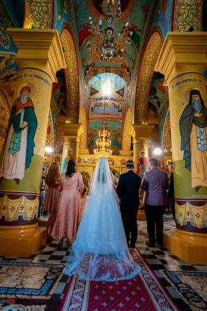 Wedding celebration in an Orthodox church featuring elaborate wall paintings and decorative architectural elements.