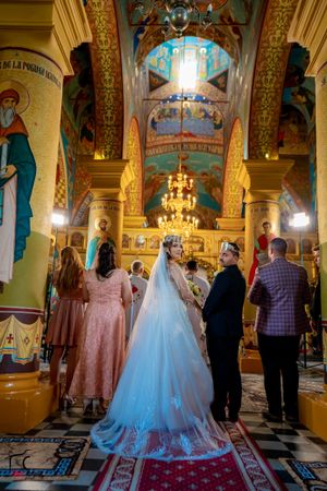 Orthodox church interior with stunning frescoes and golden details during a wedding ceremony.