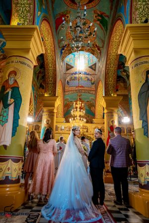 Orthodox church wedding featuring intricate wall paintings and traditional architectural elements.