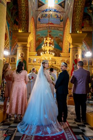 Wedding ceremony in a Byzantine church with detailed frescoes and golden ornamental features.