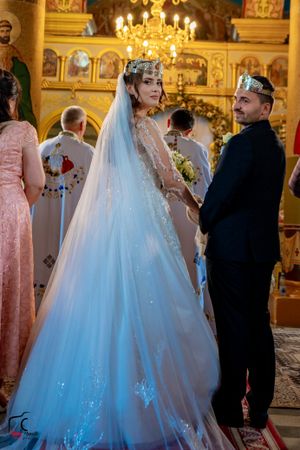 Elegant wedding celebration in an Orthodox church with ornate decorations and crystal chandeliers.